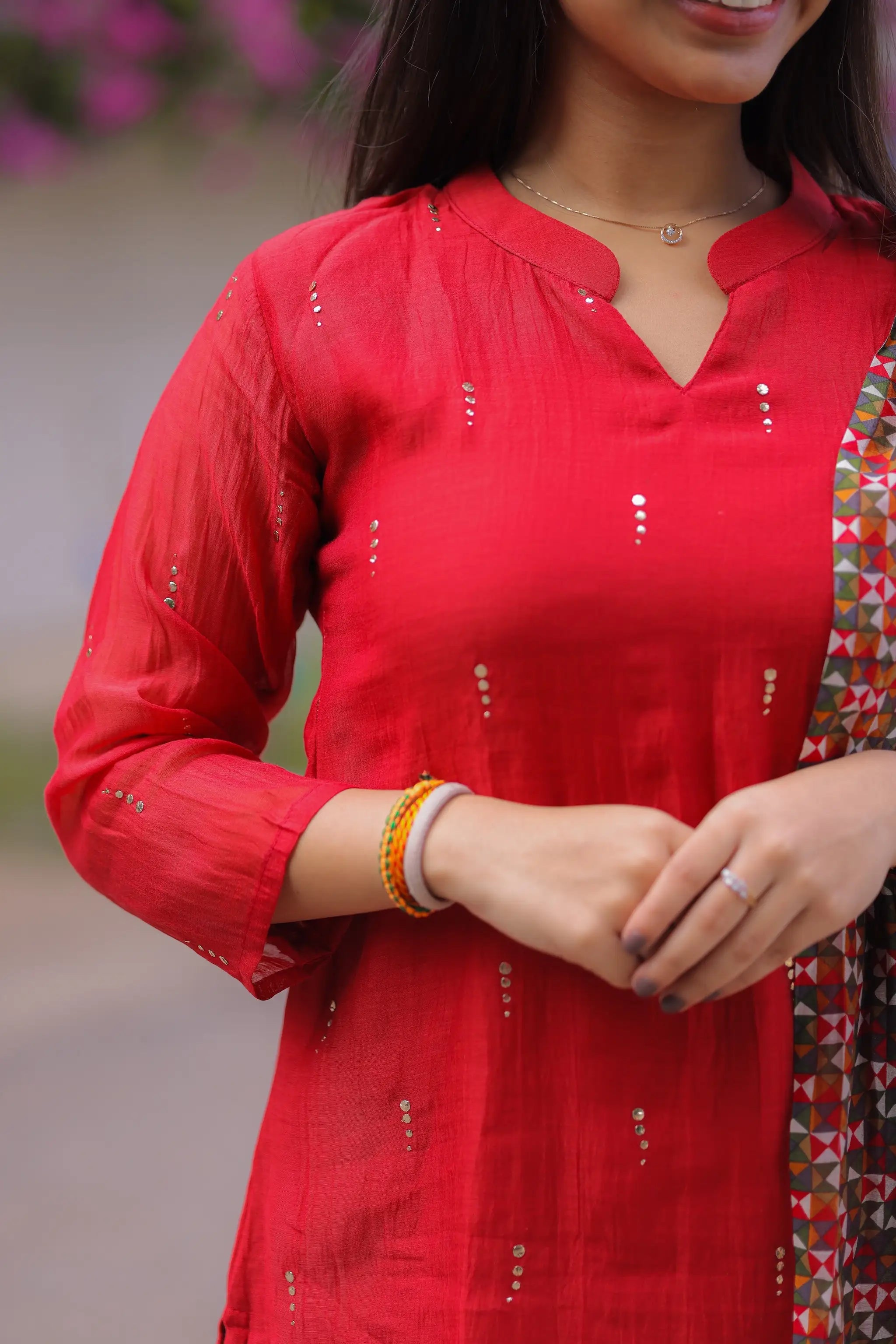 Red traditional outfit with intricate patterns, worn by a person.
