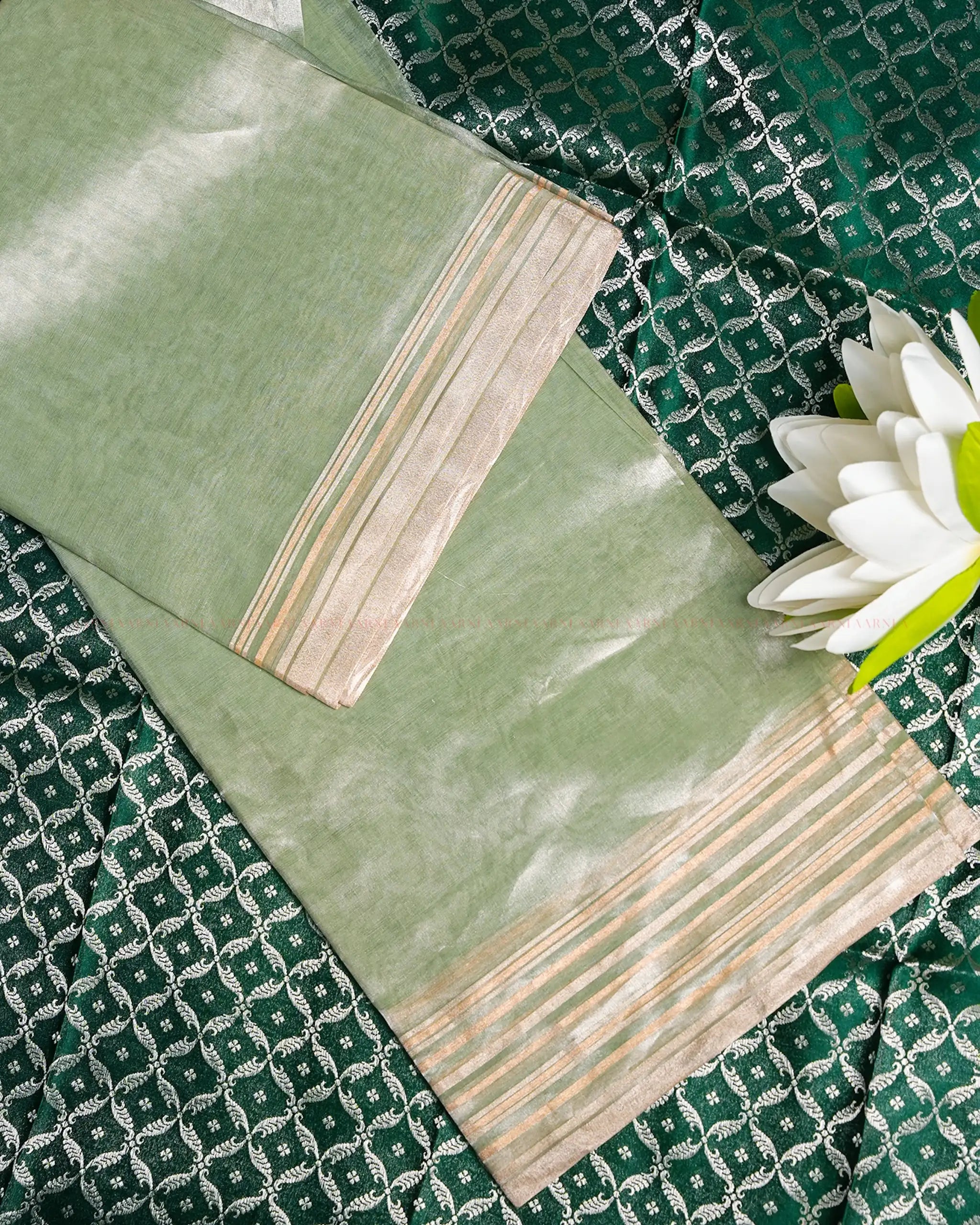 Green fabric with white patterns and a flower on a green background