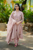 Woman in a pink traditional outfit standing outdoors with greenery in the background