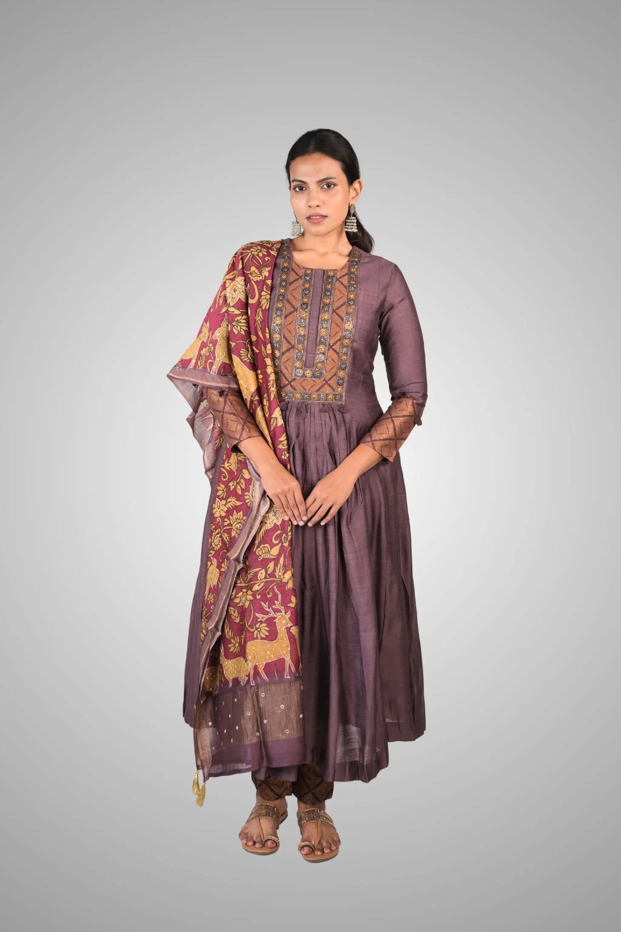 Woman wearing a traditional outfit with a purple kurta and matching dupatta on a gray background