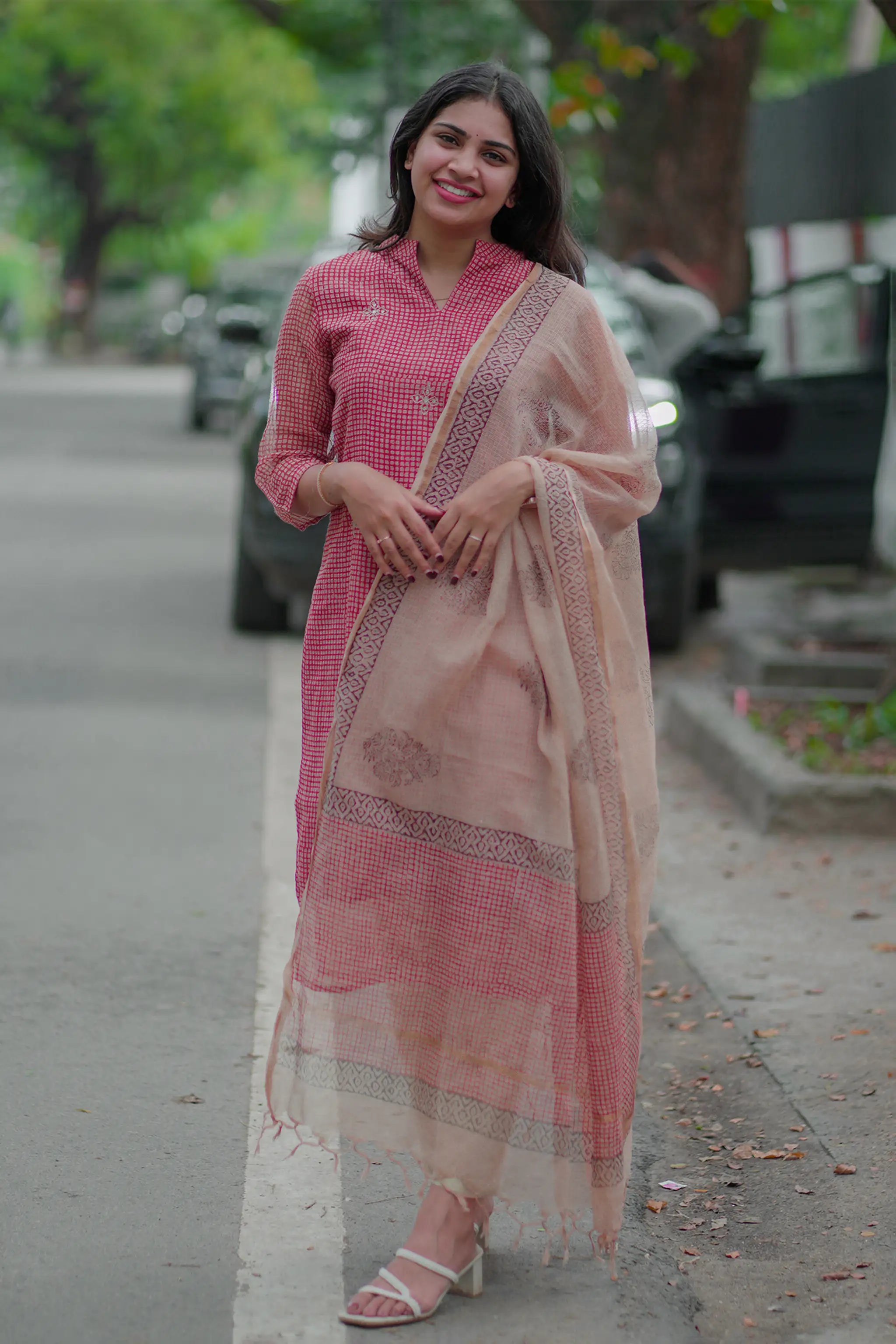 Woman in a pink traditional outfit standing on a street.