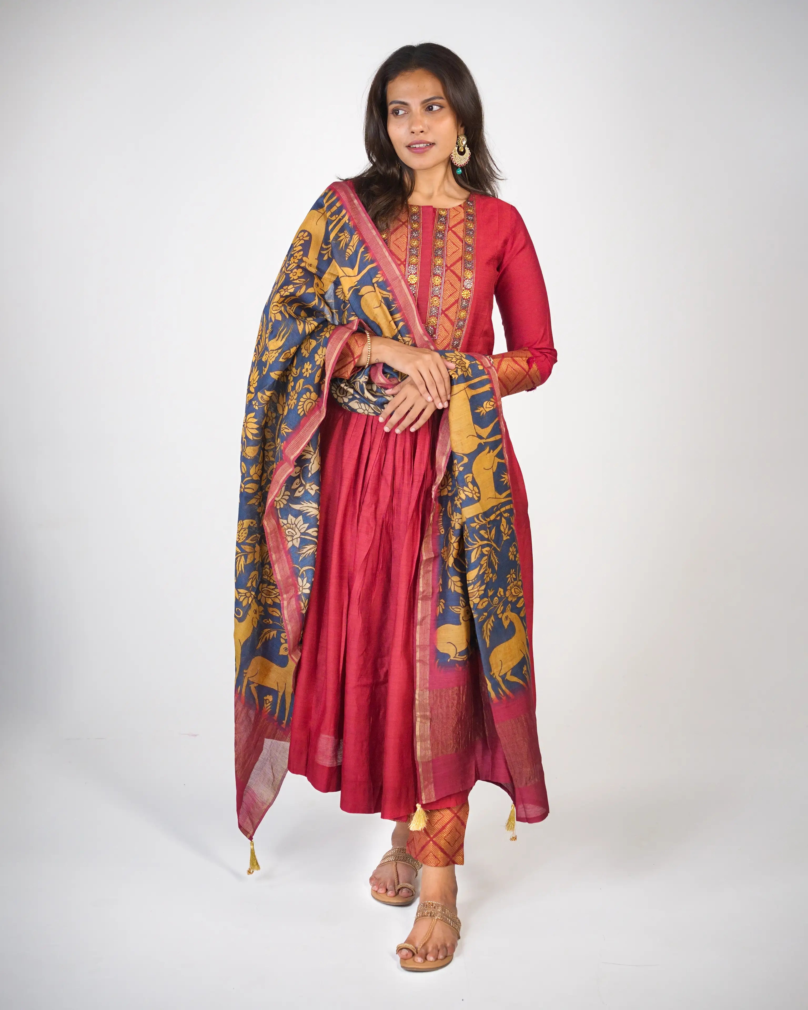 Woman wearing a red traditional outfit with a patterned dupatta on a white background