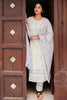 Woman in a light-colored traditional outfit standing in a doorway with wooden doors.